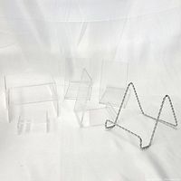 Shows all seven items: three clear acrylic plate holders, three clear acrylic risers of varying sizes, and one metal wire plate holder with triangular frame.