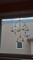 Full hanging mobile showing its size and placement within a window for scale, featuring colorful resin butterflies hanging from metal frames with glass stones.