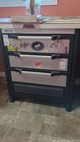 Front view of the Husky work cabinet showing three drawers, stickers on top drawer, metal handles, and key lock.