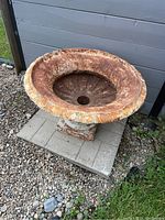 Front angled view showing the planter's wide rim with decorative floral moldings and rusted interior.