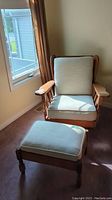 Wood frame chair and matching ottoman positioned near window on carpeted floor