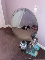 Photo showing entire mirror with etched floral design, Tiffany style lamp with stained glass-style resin shade, and vintage portable metal fan with blue base, all placed on carpet.