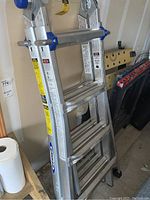 Photo of folded Werner aluminum multi ladder with visible Werner brand label and blue locking joints.