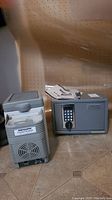 Safe and cooler side by side on tiled floor, safe with digital keypad and extra items on top