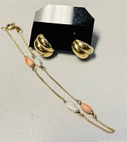 Gold bracelet with small coral and pearl beads, laid flat to show chain and clasp