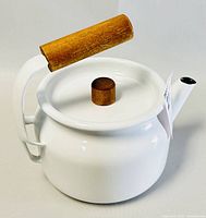 Side angled view of white enamel kettle showing wooden handle and lid knob