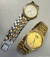 Two vintage men's SEIKO watches side by side, one gold-tone with day and date feature, one two-tone with patterned dial