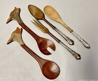 Full set of three salad tongs including the wooden bird head tongs and two sterling handled wooden utensils shown on a neutral background.