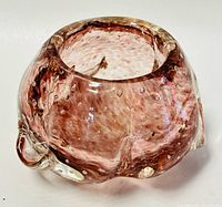 Angled side view of pinkish-brown blown art glass ashtray/bowl showing bubble texture and irregular clear glass accents.