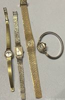 Full view of the three vintage ladies windup watches laid flat showing different band styles and dial shapes.