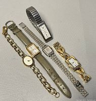 Full view of all five vintage ladies quartz watches arranged flat showing bands and dials.