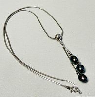 Full necklace laid flat showing chain and pendant with three freshwater pearls.