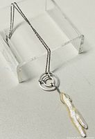 Full view of the 15 inch sterling silver chain with circular ring pendant and elongated baroque mother-of-pearl piece hanging below.