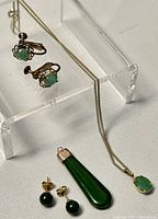 Photo showing the necklace with elongated jade pendant and both pairs of earrings together for overall lot view.