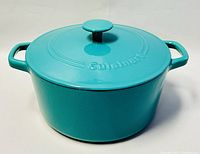 Front angled view of teal cast iron enamel casserole with lid on, showing handle and lid knob details.