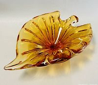 Top view of the amber blown glass leaf-shaped ashtray or bowl showing radiating textured pattern and curled edges.