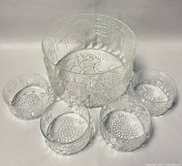 Five clear glass salad bowls arranged with one large bowl and four smaller matching bowls, showing embossed floral decorative pattern.