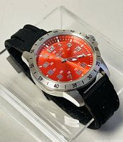 Front angled view showing red dial, silver markers, and black rubber strap.