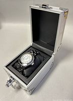 Opened aluminum box displaying the Swiss Legend men's quartz watch with a metal band.