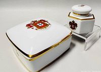 Overall angle showing the porcelain trinket box beside the hexagonal inkwell with gold and crest decorations.