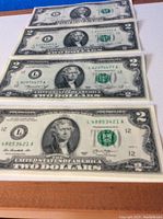 Four circulated $2 bills laid out flat showing front sides with visible wear and date years 1976, 2013, and 2017.