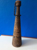 Full view of tall carved decanter showing cork and chain attached