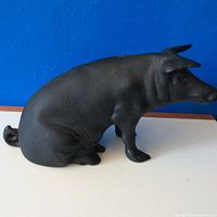 Side view of vintage cast iron pig bank showing its seated posture and detailed wrinkles.