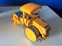 Front angle showing the yellow road roller model with details including large rollers and chrome accents.