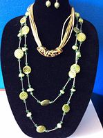Front view of jewelry display showing the two necklaces and earrings on a black bust.