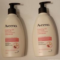 Front view of two Aveeno Creamy Oil Moisturizer bottles, 354ml each, side by side showing product label and pump tops.