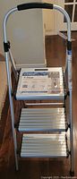 Front view of the new Cosco 3-step folding step stool showing the steps and handle with product information label on the top step.