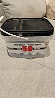 Clear plastic container holding 50 recycled golf balls with black lid, label showing quantity and quality.