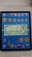 Framed commemorative set with Canadian coins and one dollar bill with provincial shields on blue background.