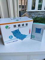 Photo showing the box packaging of the inflatable bath cushion with text and image on the box indicating use for bath comfort.