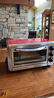 Red KitchenAid toaster oven with stainless steel front and three control knobs, closed door view