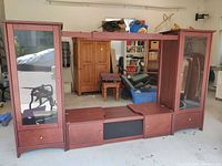 Full front view of the media entertainment unit showing two tall glass door cabinets with lighting and central expandable section.