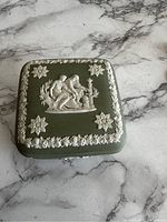 Top view of green jasperware box with white relief classical figures and flower decoration.