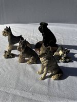Overview of six miniature dog figurines on white fabric background in sunlight showing size and detail.