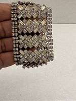 Front view of silver-tone wide rhinestone bracelet showing lattice design with baguette and round rhinestones and box clasp.