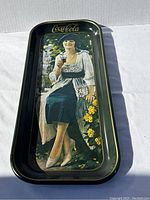 Front view of the vintage Coca Cola tin tray showing an illustrated woman holding a glass of Coke wearing vintage 1920s clothing with floral background and gold Coca Cola logo.