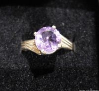 Front view showing the round faceted amethyst gemstone mounted in a four-prong setting on a .925 silver band with split shank design.