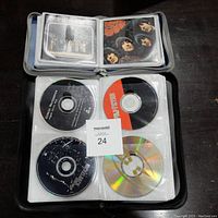 Open binder showing music CDs and cover art of various artists including The Beatles and others.