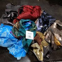 Lot of various silk scarves in assorted colors and patterns arranged in a pile.