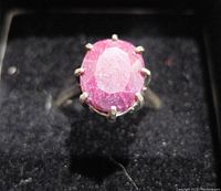 Top view of the ring showing the oval ruby gemstone set in silver prongs with faceted cut.