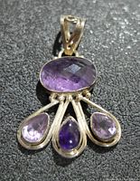 Front view of silver amethyst pendant on a textured black surface.