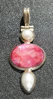 Close-up front image of the pendant showing the oval ruby gemstone center with a round pearl above and a teardrop pearl below, set in silver.