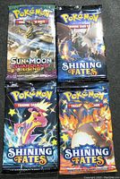 Front side of 4 sealed Pokémon TCG booster pack showing one Sun & Moon Guardians Rising and three Shining Fates packs