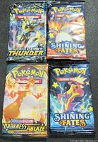 Front side showing artwork and branding of the 4 sealed Pokémon booster packs including Lost Thunder, Shining Fates, Darkness Ablaze