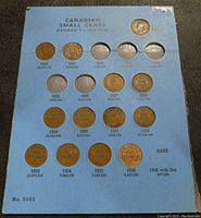 Blue folder holding Canadian Small Cent coins from era of George V, dated 1920 to 1936, showing slots for coins and text with mintage info.