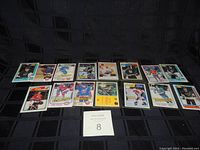 Twelve 1980s hockey cards laid out in two rows on a black fabric background, showing front images and designs.